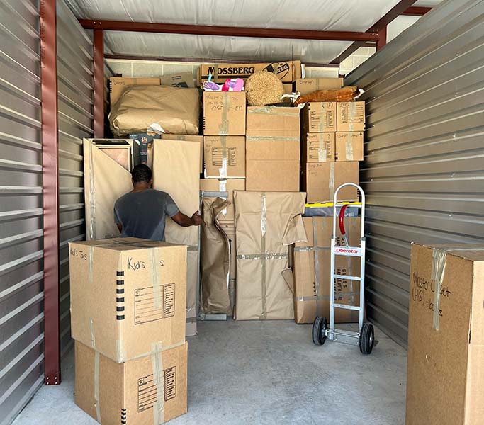 Mover organizing furniture and boxes in a storage unit, demonstrating our storage solutions.
